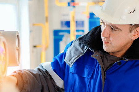 Close-up portrait of worker in hard hat and winter overalls. Authentic workflow. Gas equipment...