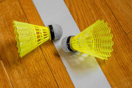 Two plastic shuttlecocks for badminton lie on sports parquet. Background. Badminton game.の写真素材