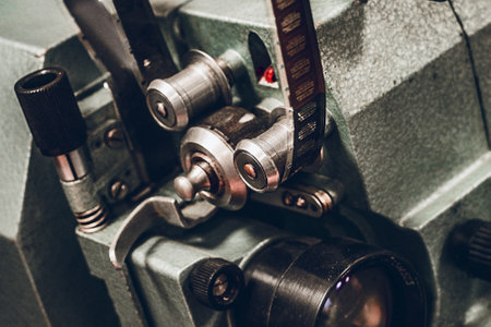 Old film camera or projector for showing movies with film strip close-up.