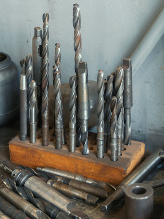 Drills for metal are on workbench in turning workshop. Tool storage. Industrial background.