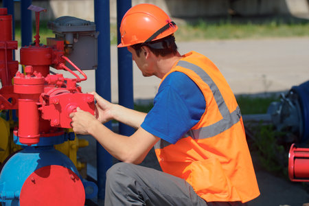 Maintenance of industrial gas equipment. working man in hard hat checks equipment in warehouse on...