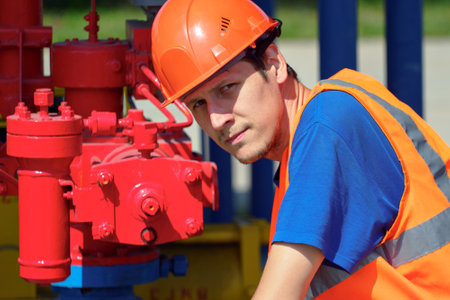 Maintenance of industrial gas equipment. working man in hard hat checks equipment in warehouse on summer day.の写真素材
