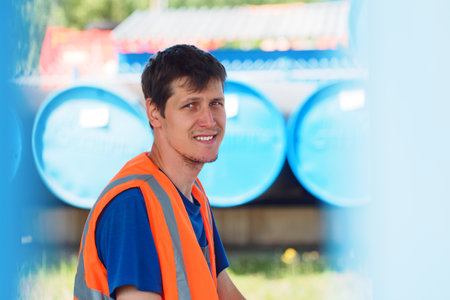 Portrait of young man in construction vest outside on summer day. Storekeeper or builder is looking...