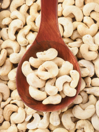 Peeled cashew nuts lie in wooden spoon. Top view of nuts close-up. Advertising photography for marketplaces or online stores.の写真素材
