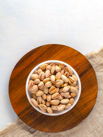 Cup with selected in-shell pistachios on light background with copy space. Advertising photography for marketplaces. Top view. Healthy nuts.の写真素材