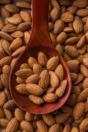 Dried almonds. Almond kernels lie in wooden spoon. Top view of nuts close-up. Advertising photography for marketplaces or online stores.の写真素材