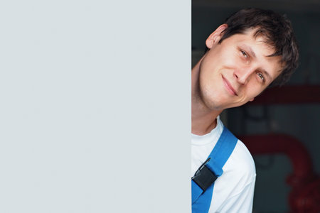 Portrait of happy caucasian worker with copy space. Worker looks out from behind wooden door and smiles.の写真素材