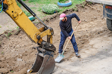 Repair and improvement of road and surrounding area. Handyman with shovel repairs road surface on...