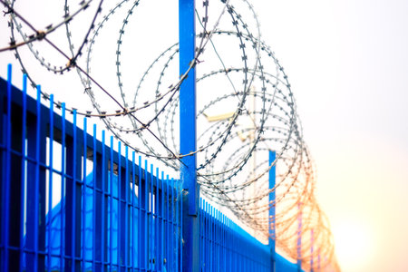 Blue metal fence with barbed wire on top. Fencing around perimeter. background.の写真素材