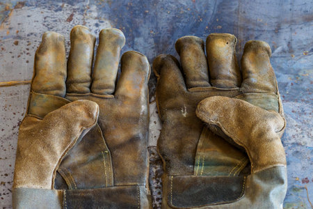 Worn welding gloves lie on table, palms up. Top view of working gaiters. Background.の写真素材