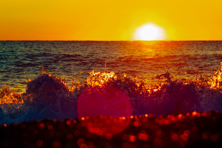 Sunset on sea. Sun sets behind horizon of sea. Splash of waves. Sunset landscape.の写真素材