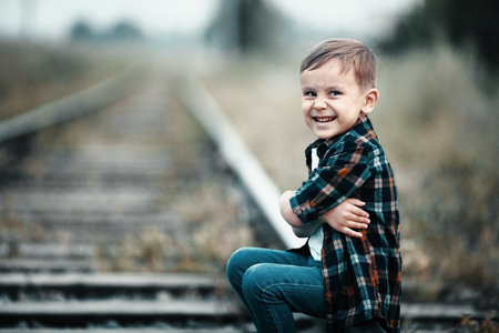 Lonely boy sits on railroad tracks. Mischievous man ran away from home. Bad boy.の写真素材