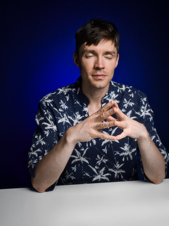 Caucasian man sits in home studio with his eyes closed and meditates. Concentration and positive attitude. Young man gathers his courage. Antidepressive technique.の写真素材