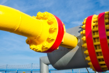 Gas industry pipe connection unit. Bolted connection of pipes for gasification. Transportation of gas through pipes. Gas distribution station equipment. Gas transportation enterprise. Bright background. Pipes are red and yellow.の写真素材