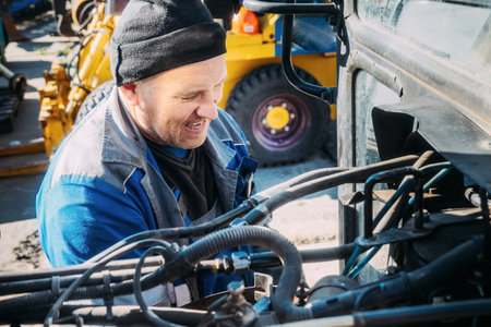 Mechanic repairs engine of tractor or heavy equipment. Farmer inspects and diagnoses agricultural...