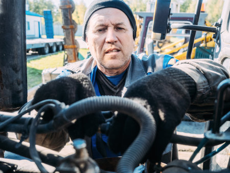 Mechanic repairs engine of tractor or heavy equipment. Farmer inspects and diagnoses agricultural machinery.の写真素材