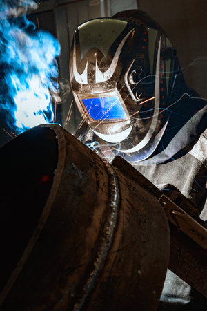 welder in protective mask welds metal with arc welding machine.の写真素材