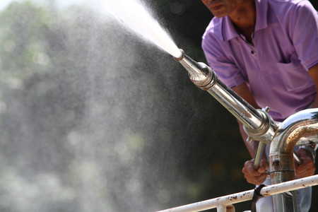 Hand holding water hose to prevent fire on carの写真素材