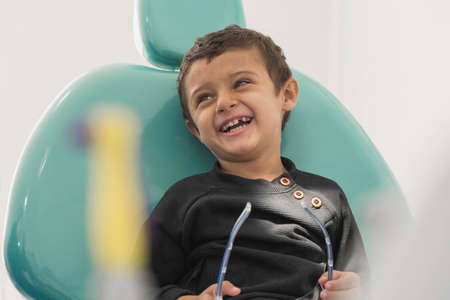 Child sitting on a dentist's chair laughing.の写真素材