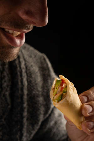 Santa Fe, Argentina, August 3, 2021: Man eating Argentinian empanadas. Selective focus.のeditorial素材