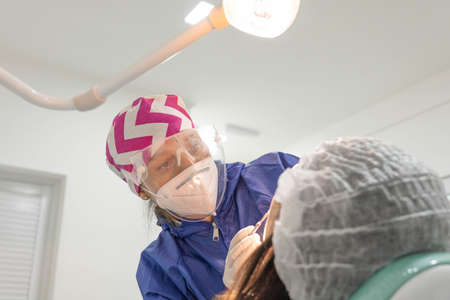 Young female dentist curing patient's teeth. Close-up shot, teeth care and medicine concept