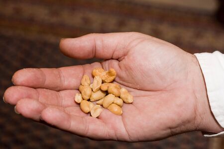 Man's hand offering some salted peanutsの写真素材