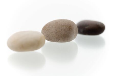 Very high resolution image.Three different colored pebbles in a row. On a white surface with reflection. High key shot with shallow depth of field. Focus on middle pebble.の写真素材