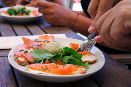 Men's hands eating a delicious salmon salad on a wooden deskの写真素材
