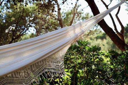 Beautiful hammock with knitted lace border hanging on a shaded place in a garden