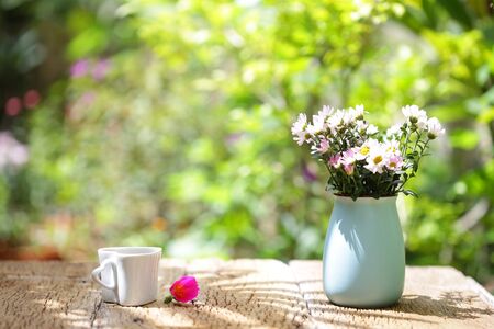 Flowers with vintage pot and heart shaped cup on wooden tableの写真素材