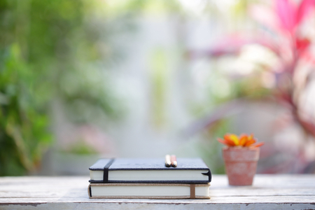 Diary notebook with pens and small plant pot on wooden tableの写真素材