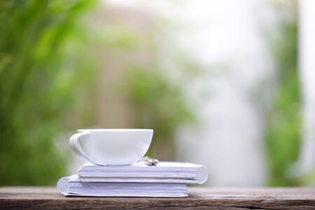 White coffee and diary notebooks on brown wooden table at outdoor