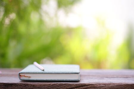 Green diary notebook and pencil on wooden table