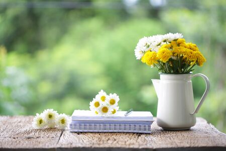 Flower in metal pot with diary on wooden table at outdoorの写真素材
