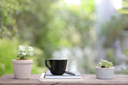 Black coffee cup with small plant pot  and notebook on wooden table relax sceneの写真素材