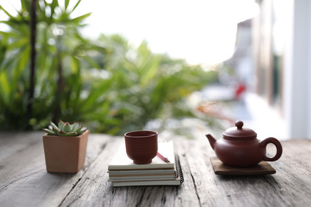 Traditional clay teapot and tea pot with succulent plant with books on old wooden table relax home outdoor workspaceの写真素材