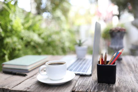 White coffee cup and laptop with pencil stationary outdoor work spaceの写真素材
