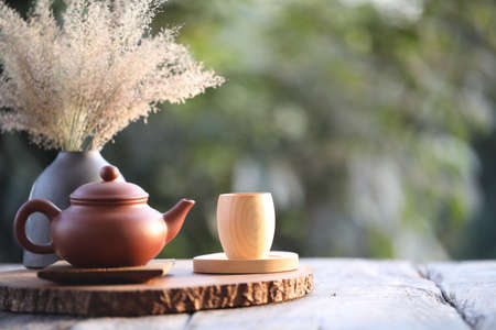 Bamboo wooden tea cup and brown clay kettle with dry flower pot on tableの写真素材