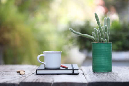 White coffee mug an notebooks with cactus pot on wooden tableの写真素材