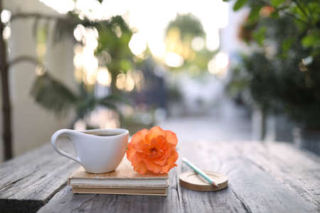 Coffee cup and brown kraft notebook and pencil with rose flower on wooden tableの写真素材