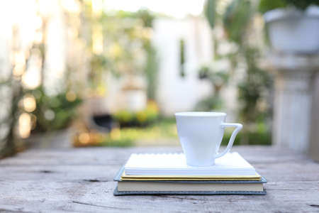 white ceramic cup and notebooks on wooden tableの写真素材