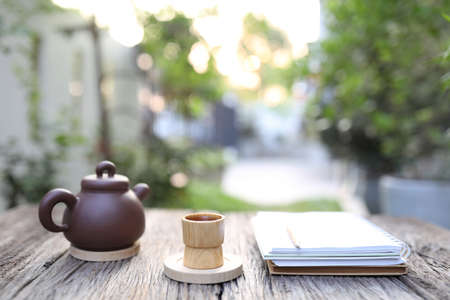 Bamboo cup and tea pot with notebooks on wooden tableの写真素材