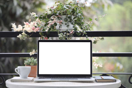 Laptop white mock up blank screen and notebooks on white table outdoorの写真素材