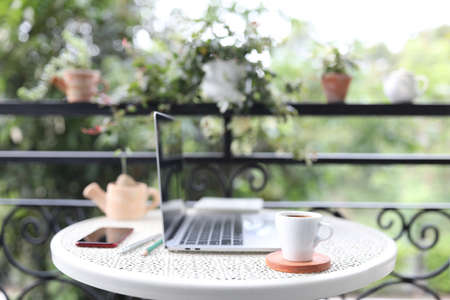 Silver laptop side view white mock and coffee cup with notebooks on white table outdoorの写真素材