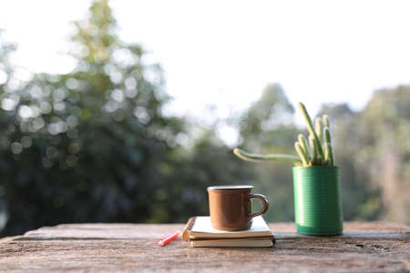Brown coffee cup and cactus in green pot on wooden tableの写真素材