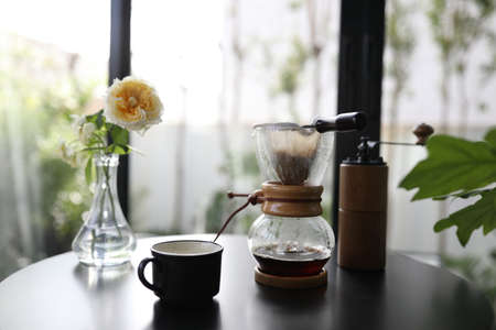 Black Coffee cup with coffee drip and Coffee grinder pot on black tableの写真素材