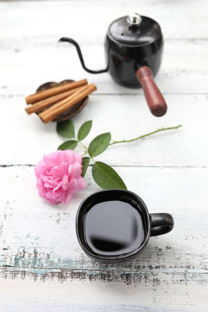 Black coffee cup and pink rose flower and drip pot on white tableの写真素材