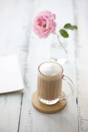 Latte and rose flower with notebook on vintage old white table