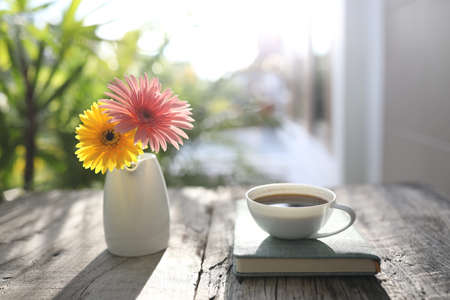 White coffee cup and notebook with gerbera flowersの写真素材