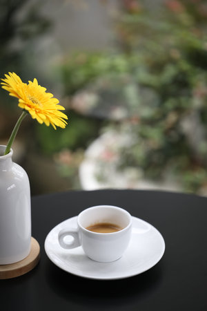 Coffee in a white ceramic cup with yellow gerbera flowerの写真素材